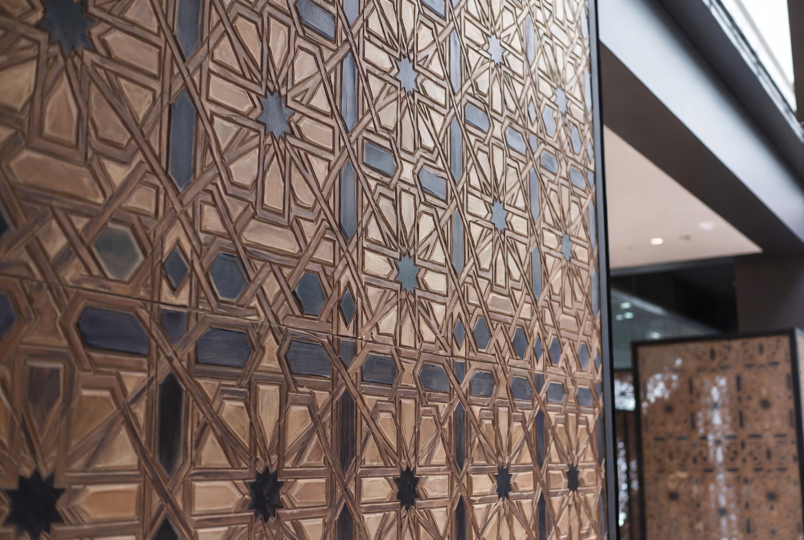 Arabic geometric wood screen with repeating star and polygon pattern across an interior panel.