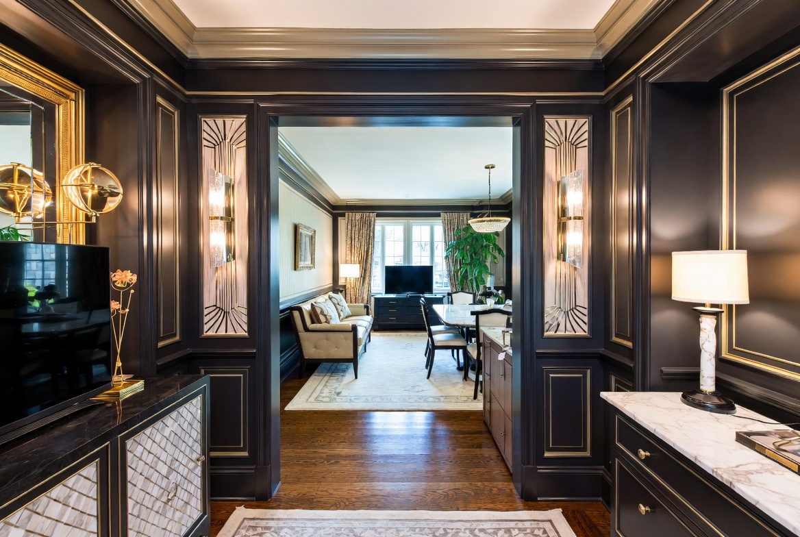 Art Deco-inspired interior with dark paneling, metallic detailing, and connected living spaces.