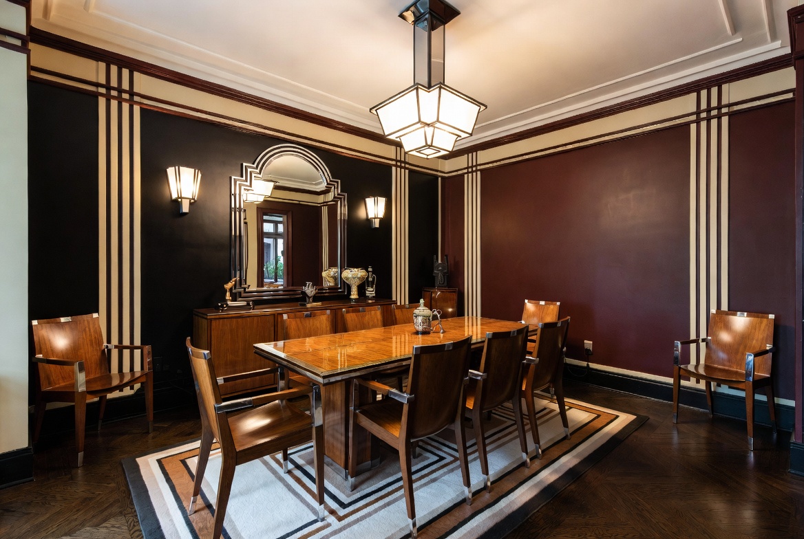 Art Deco dining room with polished wood furniture, geometric wall detailing, and angular period lighting.