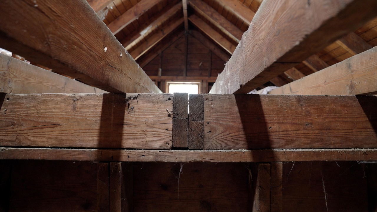 Older attic framing can help reveal support lines, but joist laps and splices need to be read carefully above the wall below.