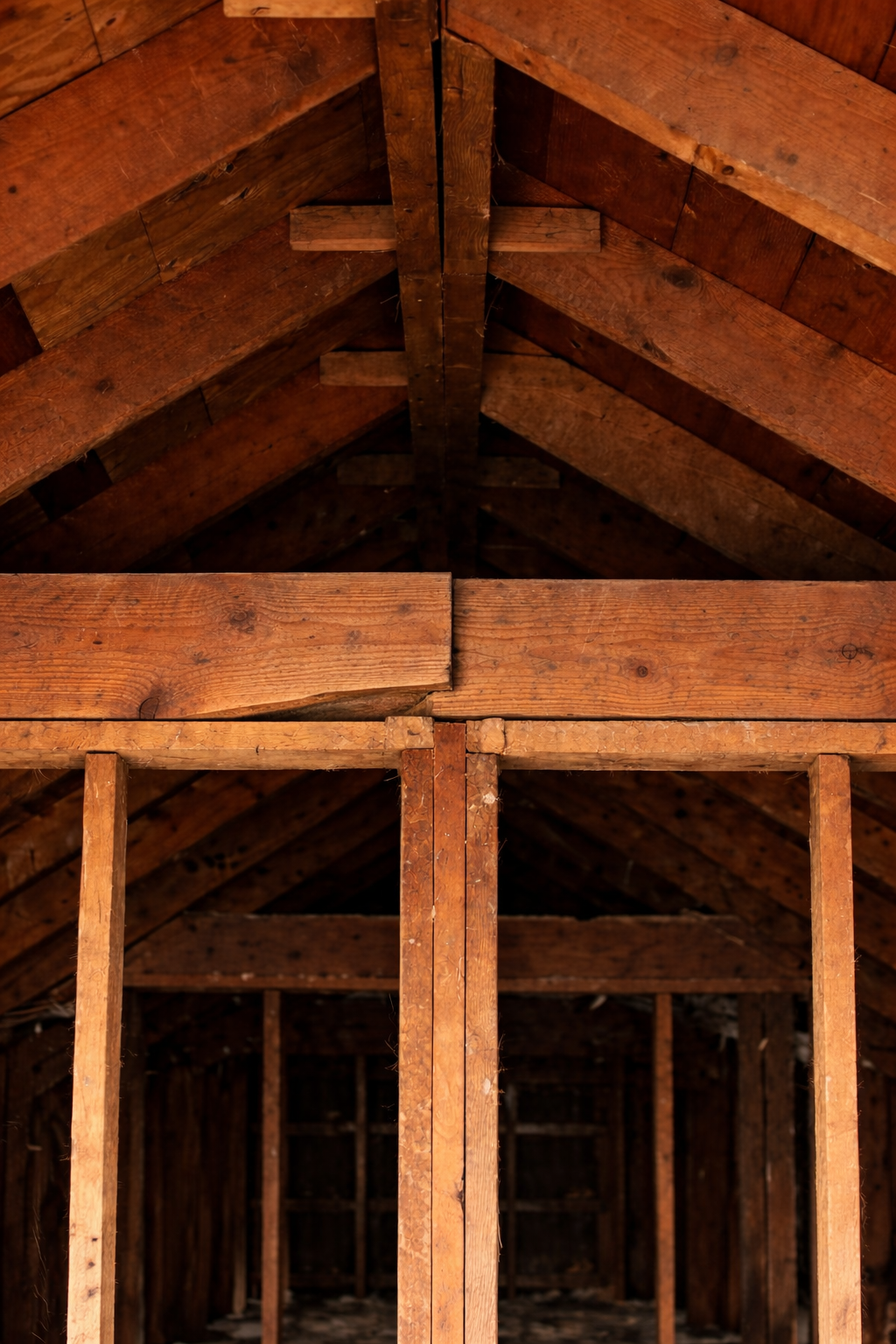 Older attic framing showing ceiling joists lapping over an interior wall line in a single-story house.