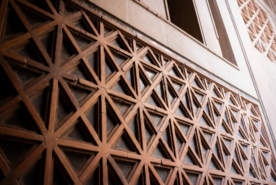 Geometric brick lattice pattern forming repeated star shapes across a traditional wall surface.