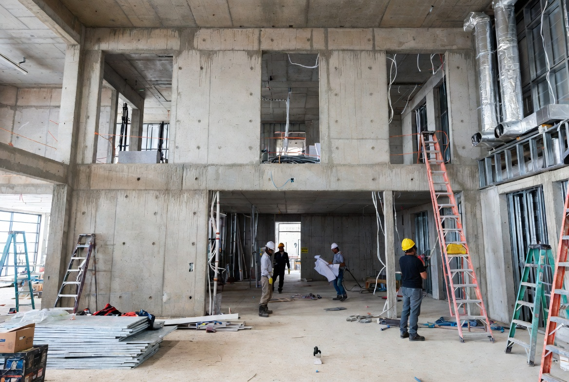 Exterior perspective of a healthcare building under construction with roof framing and partially completed envelope.