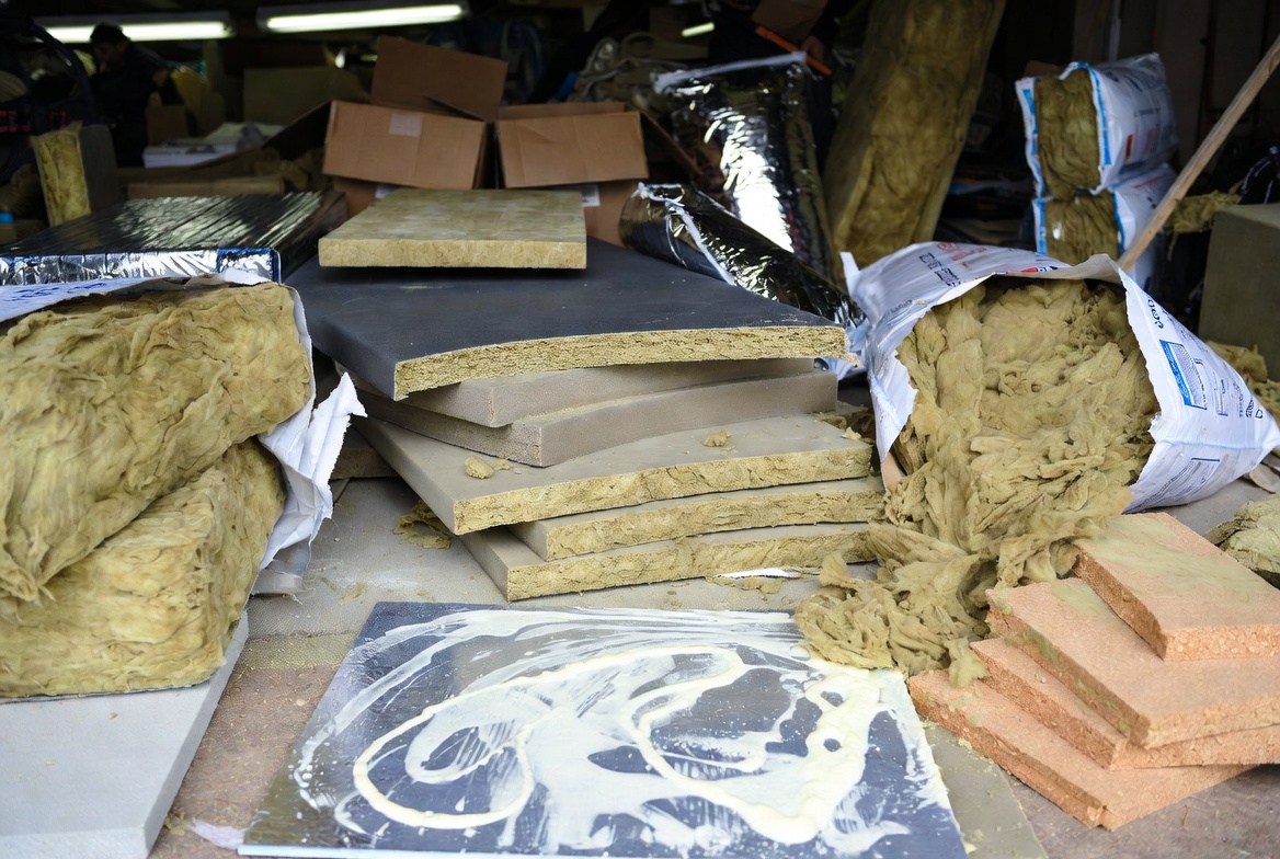 Mixed insulation materials piled together in a workshop, showing messy handling that can reduce insulation performance.