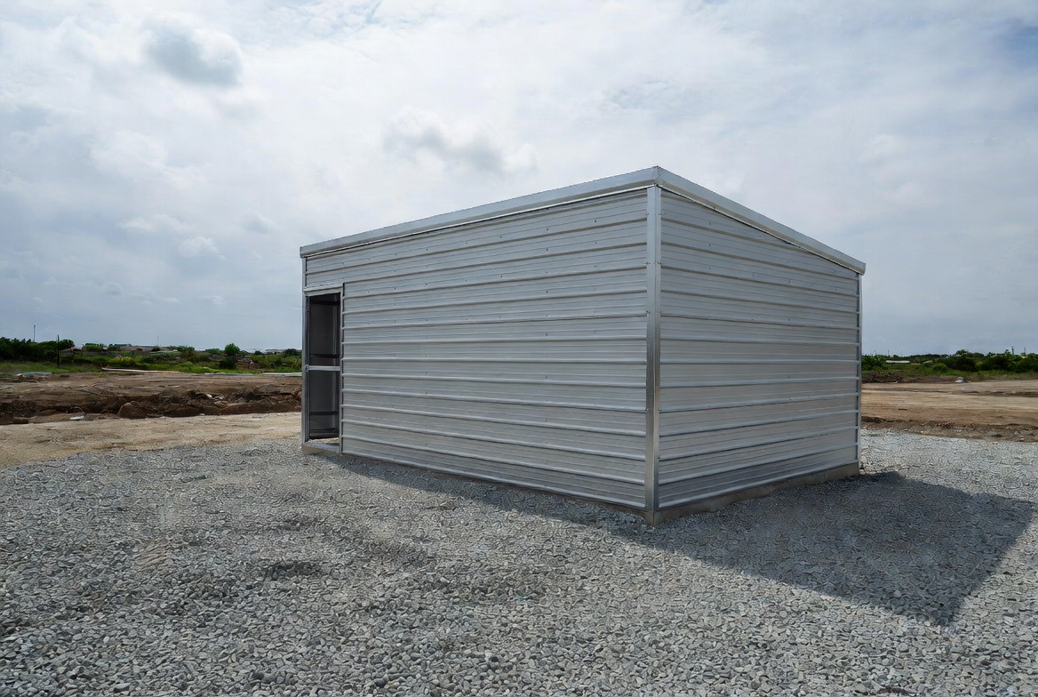 Small prefab metal building on a compacted gravel pad for basic storage use.