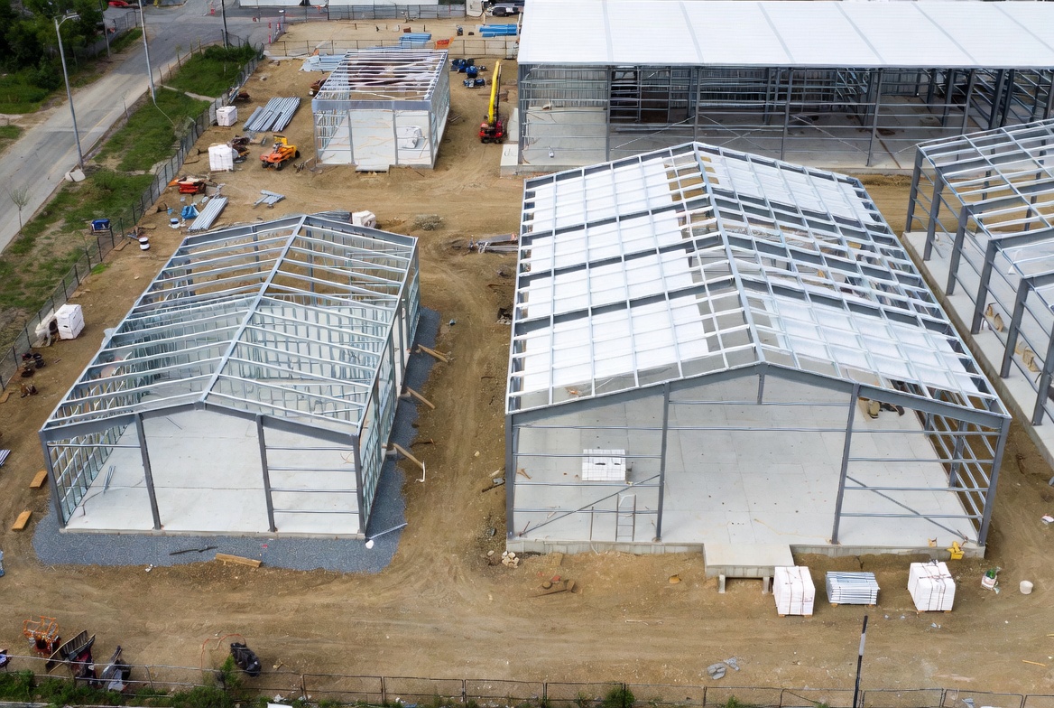 Prefab metal building shells at different stages of construction on a commercial jobsite.