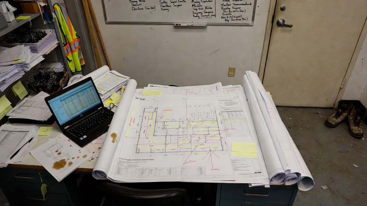 Pre-construction planning documents, schedules, and marked-up drawings in a site office