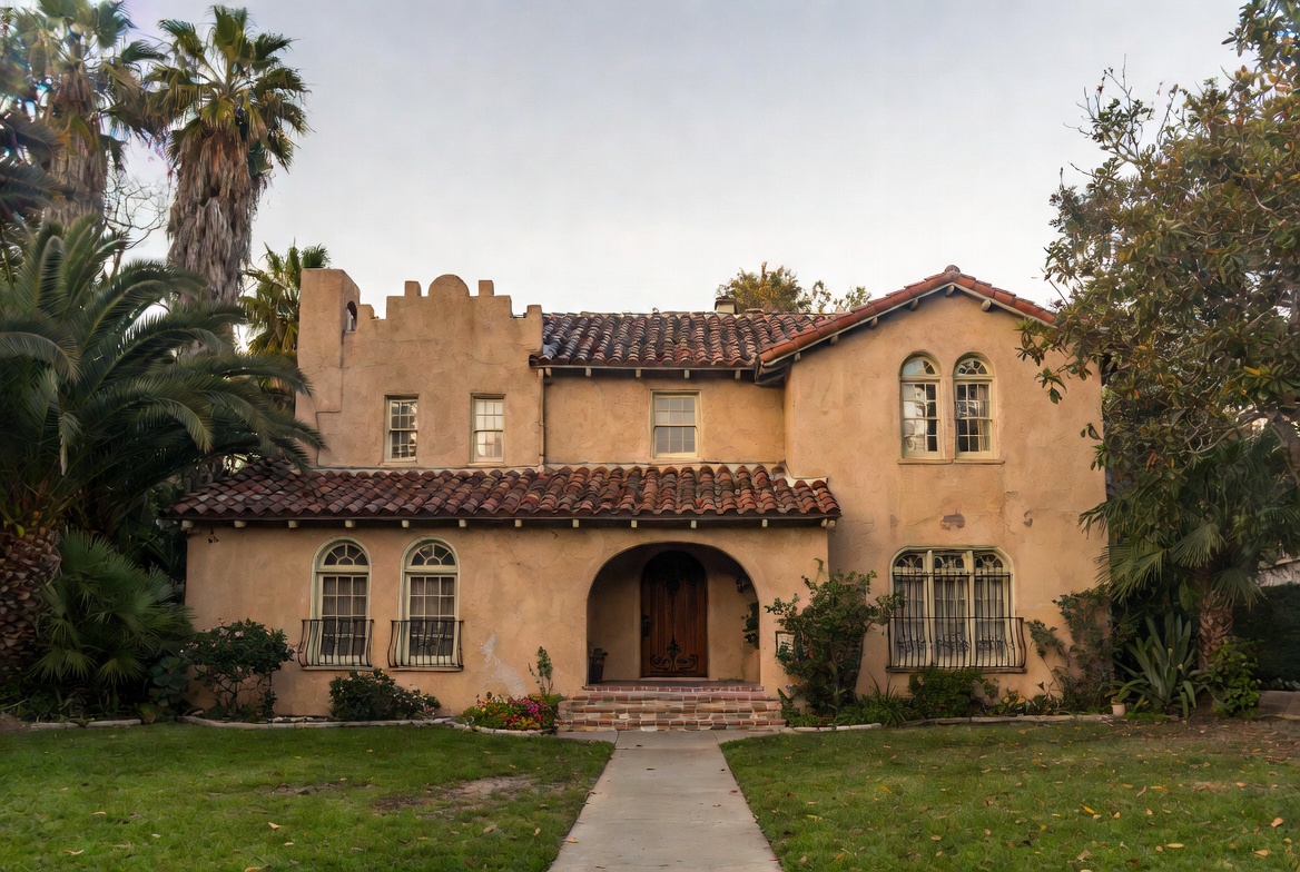 Spanish Colonial Revival house with stucco walls, clay tile roof, arched entry, and wrought-iron grilles.