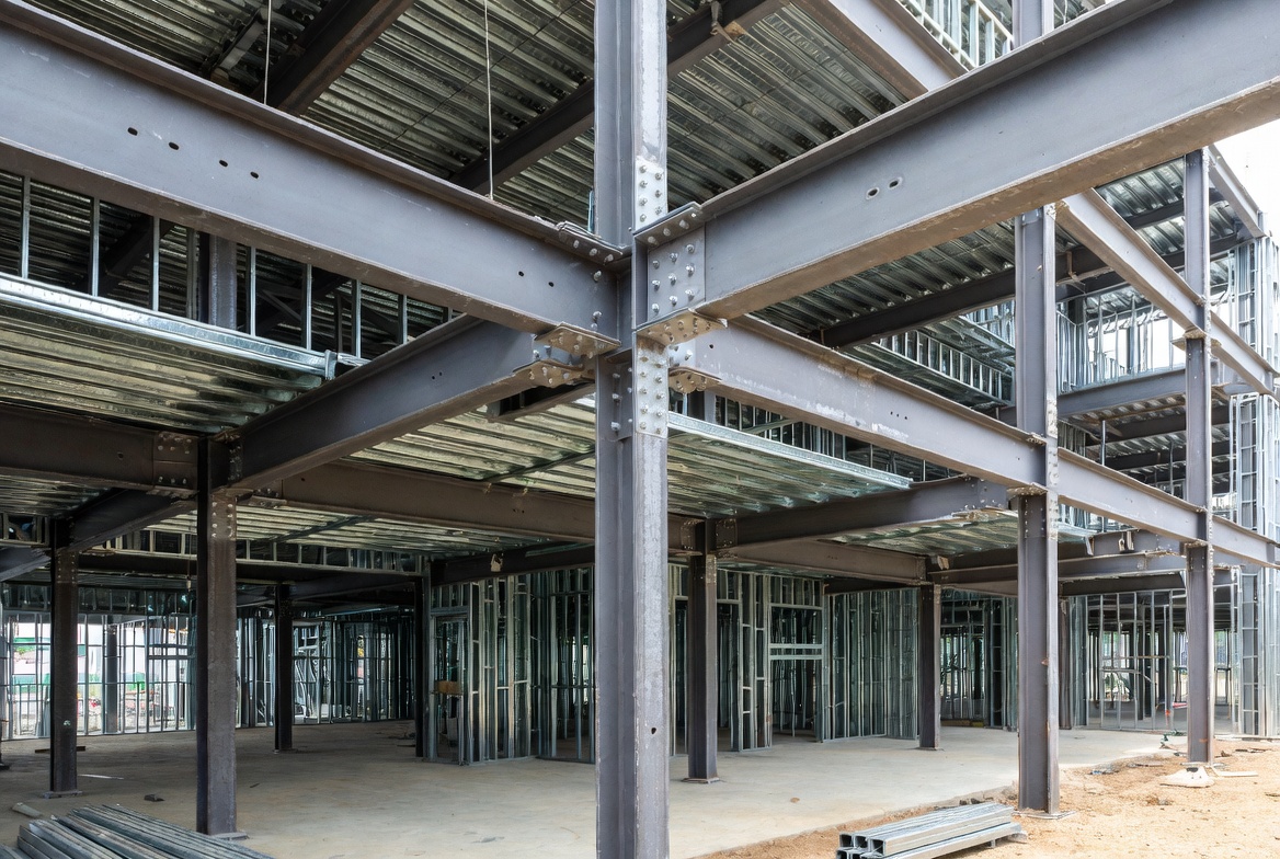 Structural steel frame with bolted beam-column connections inside a building under construction.