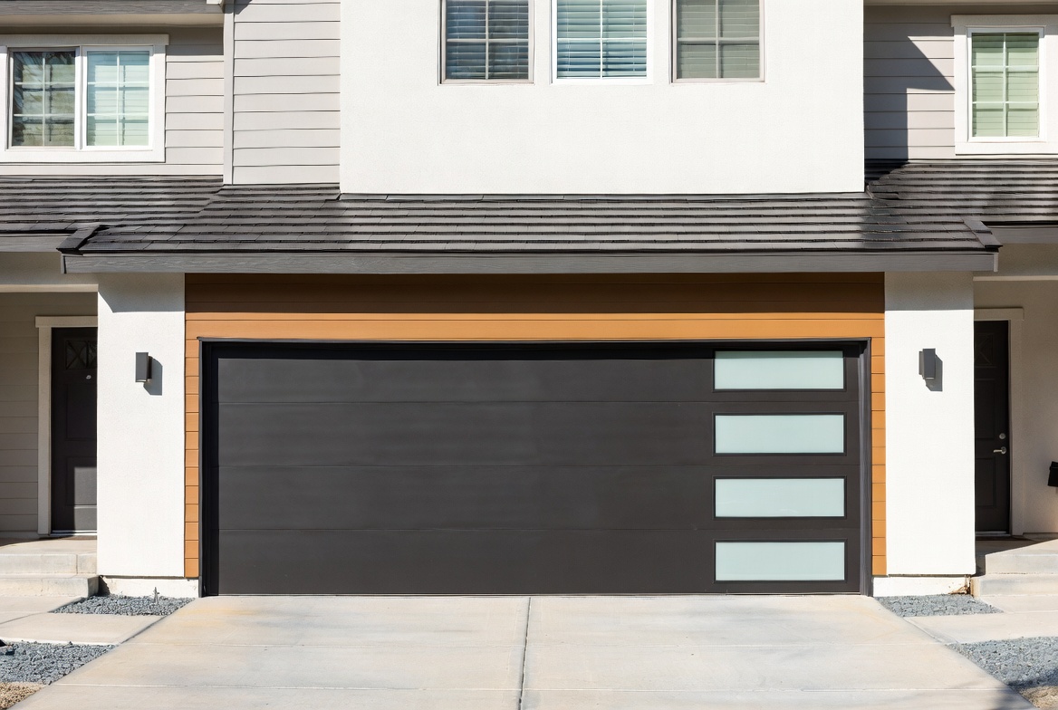 Modern garage door with dark flush panels, a wood accent strip, and frosted glass inserts.