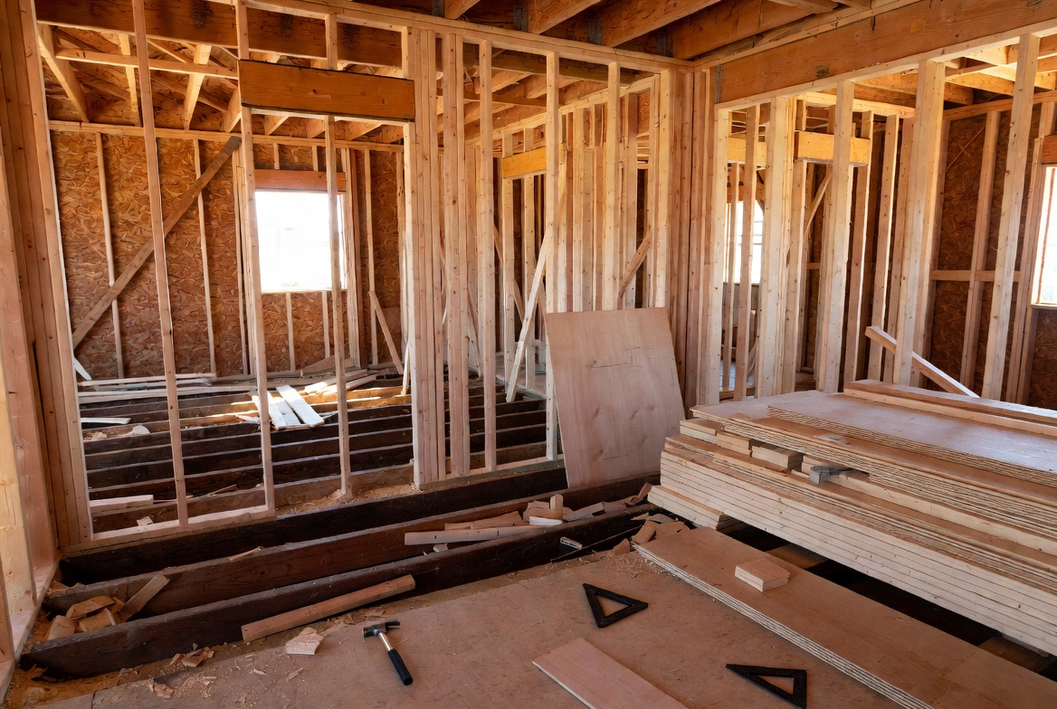 Wood framing and plywood materials inside a residential building under construction.