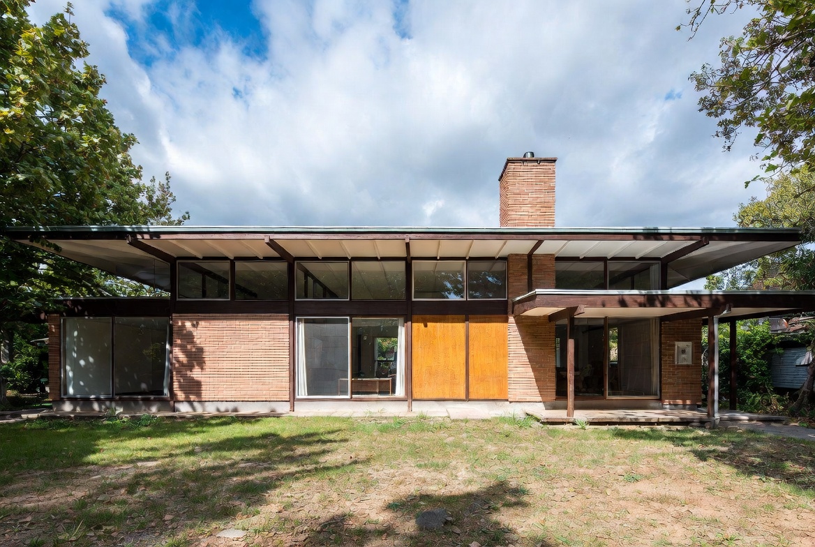 1960s ranch-style house with low roofline, brick, and wide front windows.