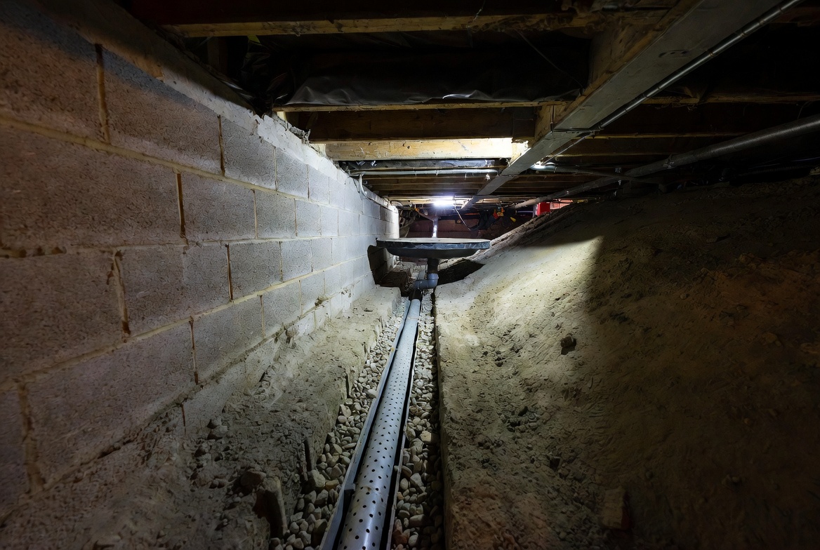 Interior crawl space drainage pipe running along a perimeter trench.