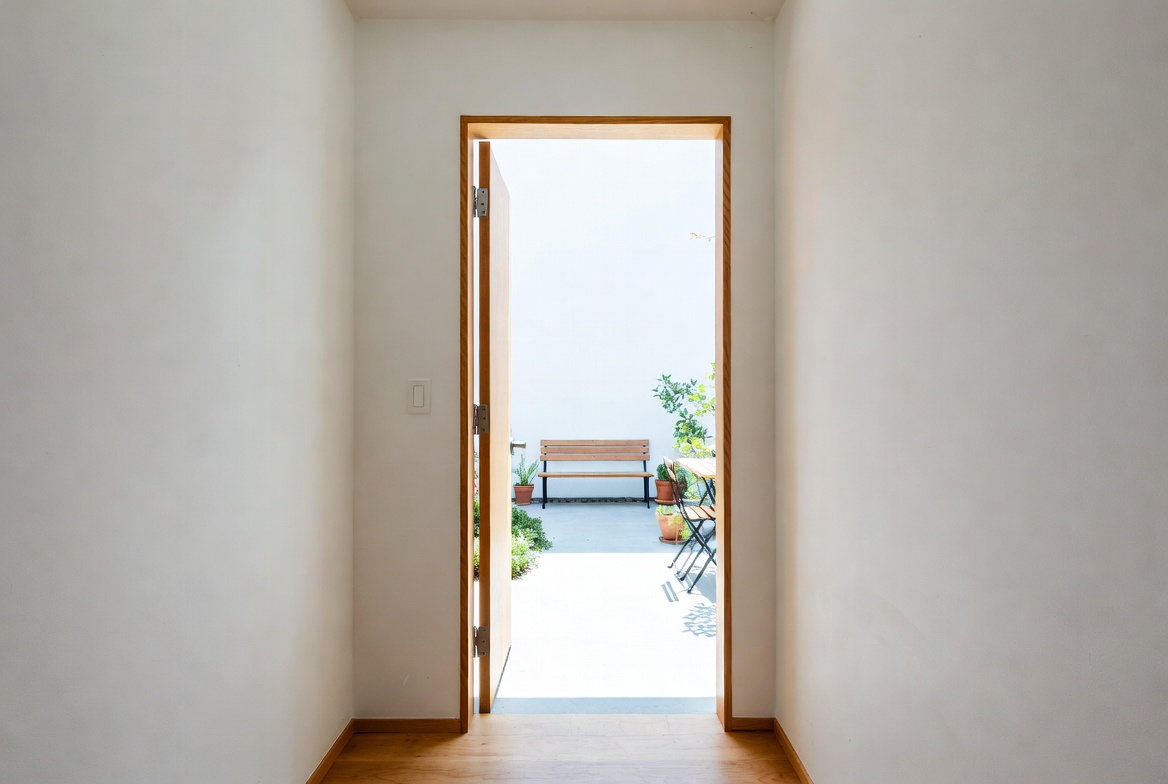 Narrow interior hall opening to a small patio with bench seating and a simple clear path.