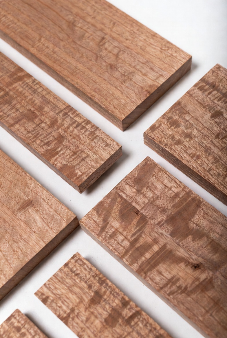 Several mahogany boards arranged on a white background showing varied grain and surface figure.