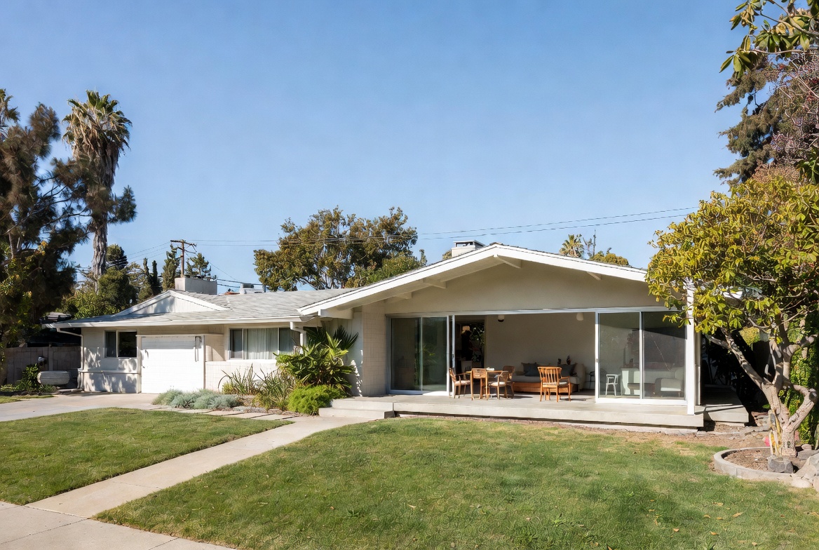 Modern addition to a ranch house with a new gabled living volume and wide sliding glass opening.