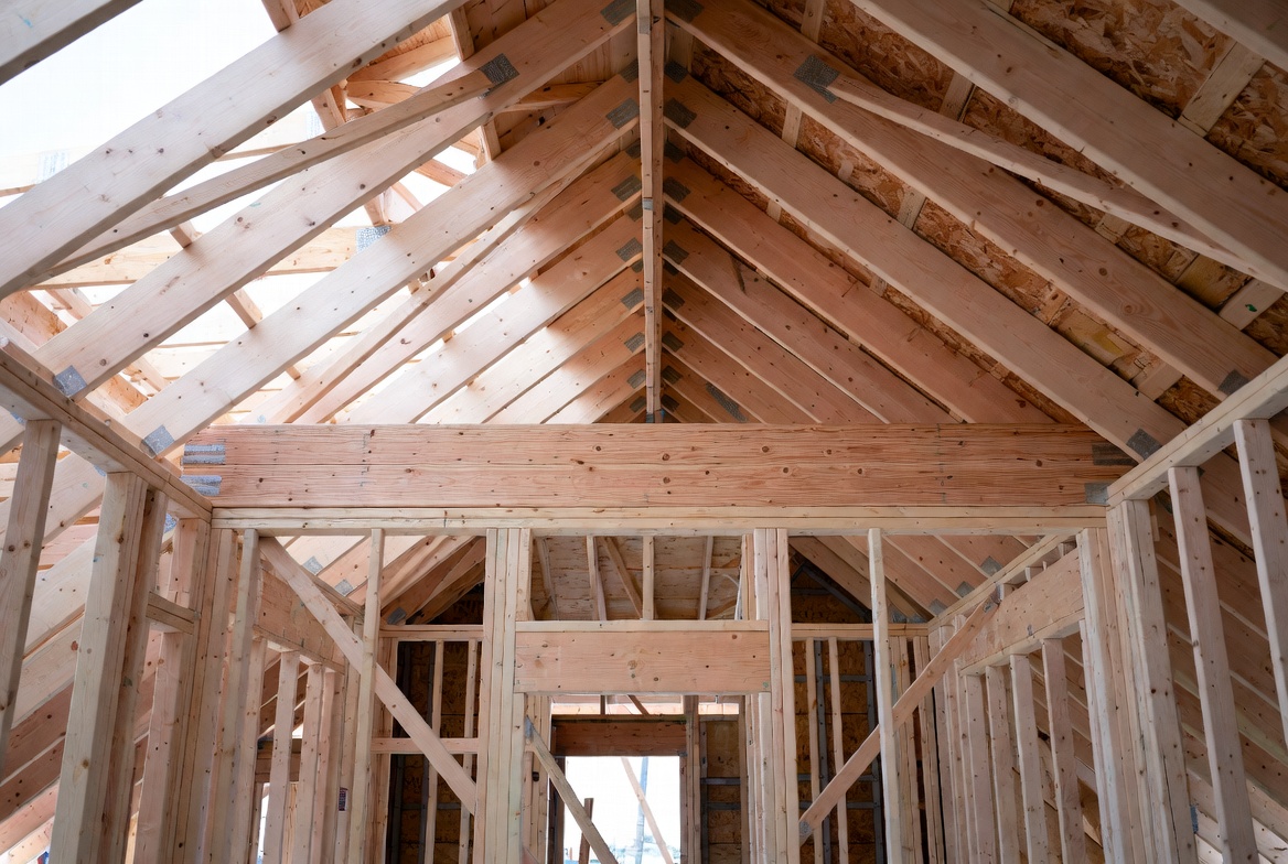 Temporary diagonal brace installed across timber roof trusses during residential framing.