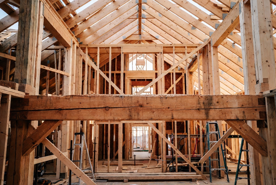 Heavy timber tie beam spanning between vertical posts inside a timber roof frame.