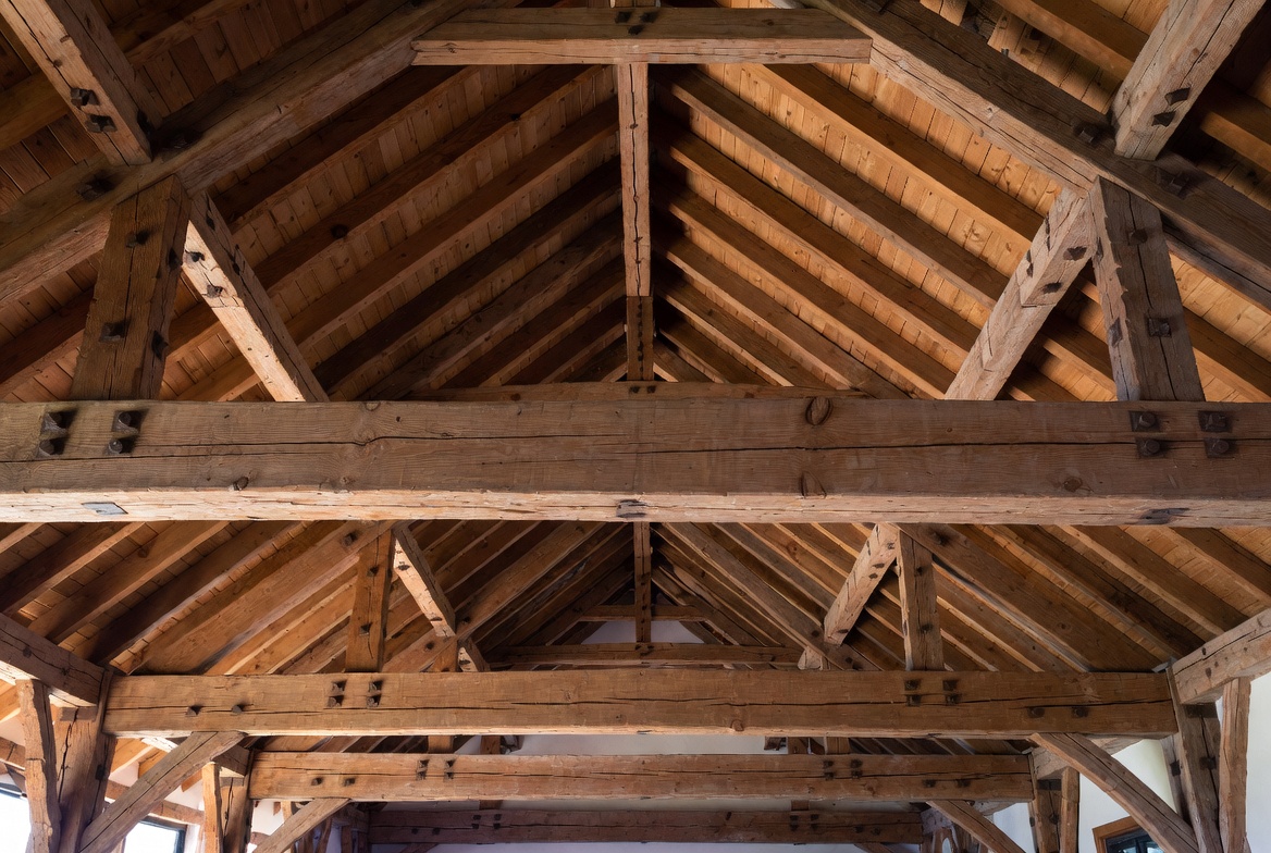 Repeated heavy timber trusses across a vaulted ceiling with exposed wood roof framing.