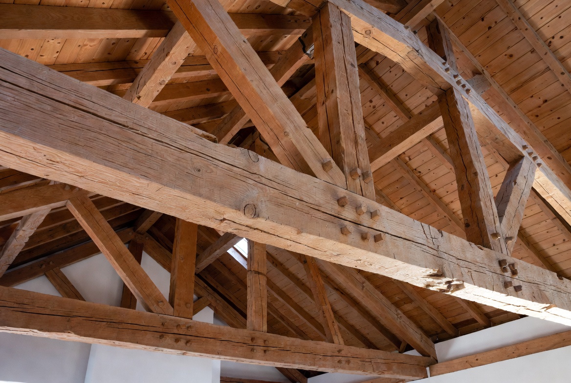 Heavy timber truss frame with diagonal braces, tie beam, and exposed roof decking.