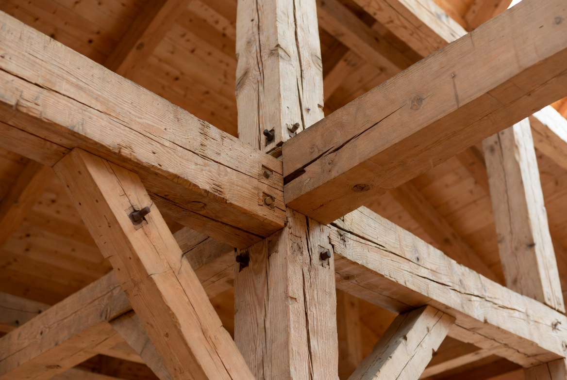 Close view of a timber truss joint with intersecting beams, braces, and visible connection details.