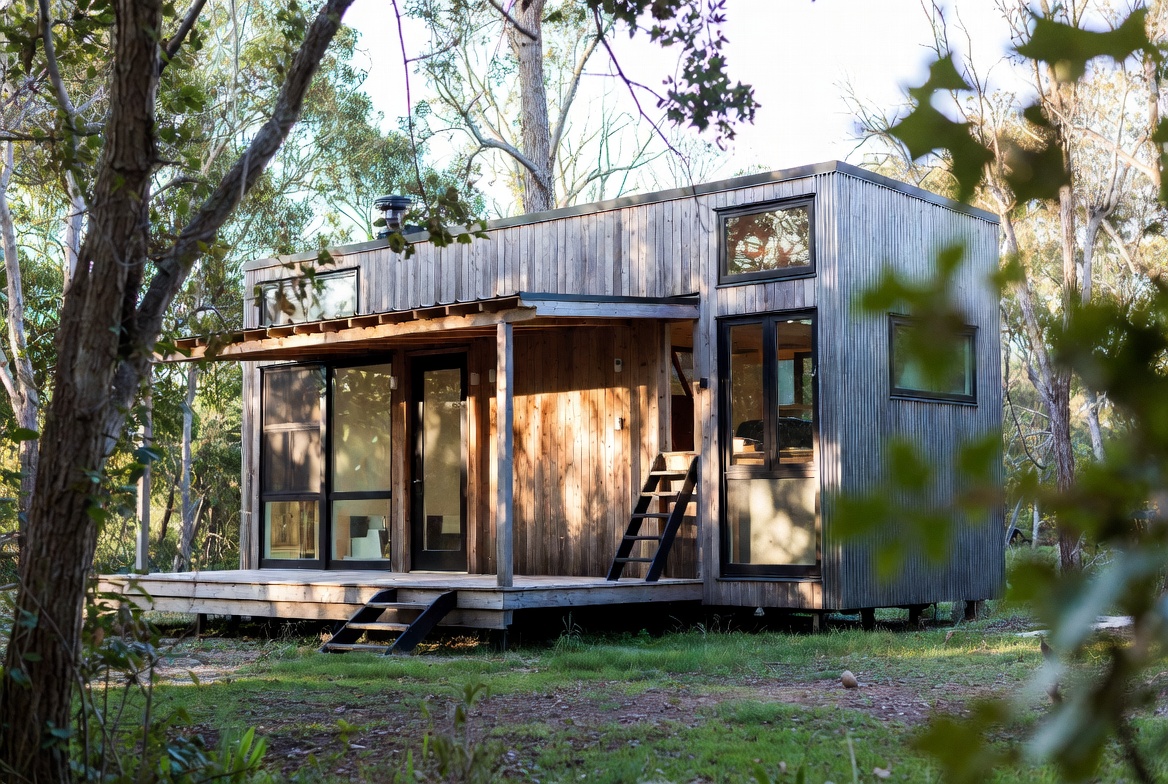 Modern tiny home with corrugated cladding, timber siding, and compact porch.