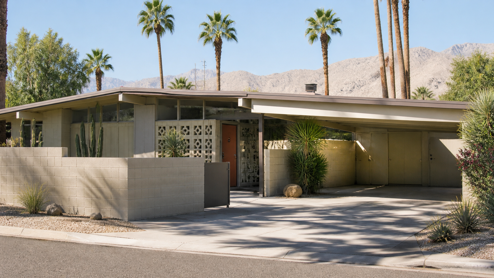 A 1950s Palm Springs desert modern house with flat roof, breeze-block screen wall, carport, concrete block wall, palms, and desert planting.