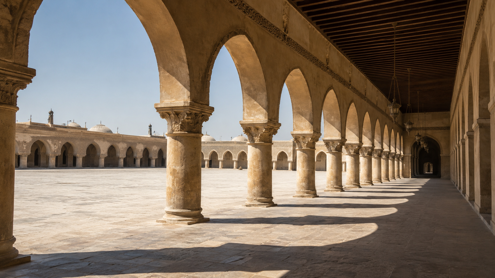 Islamic arcade with repeated stone arches casting shade across a courtyard walkway.