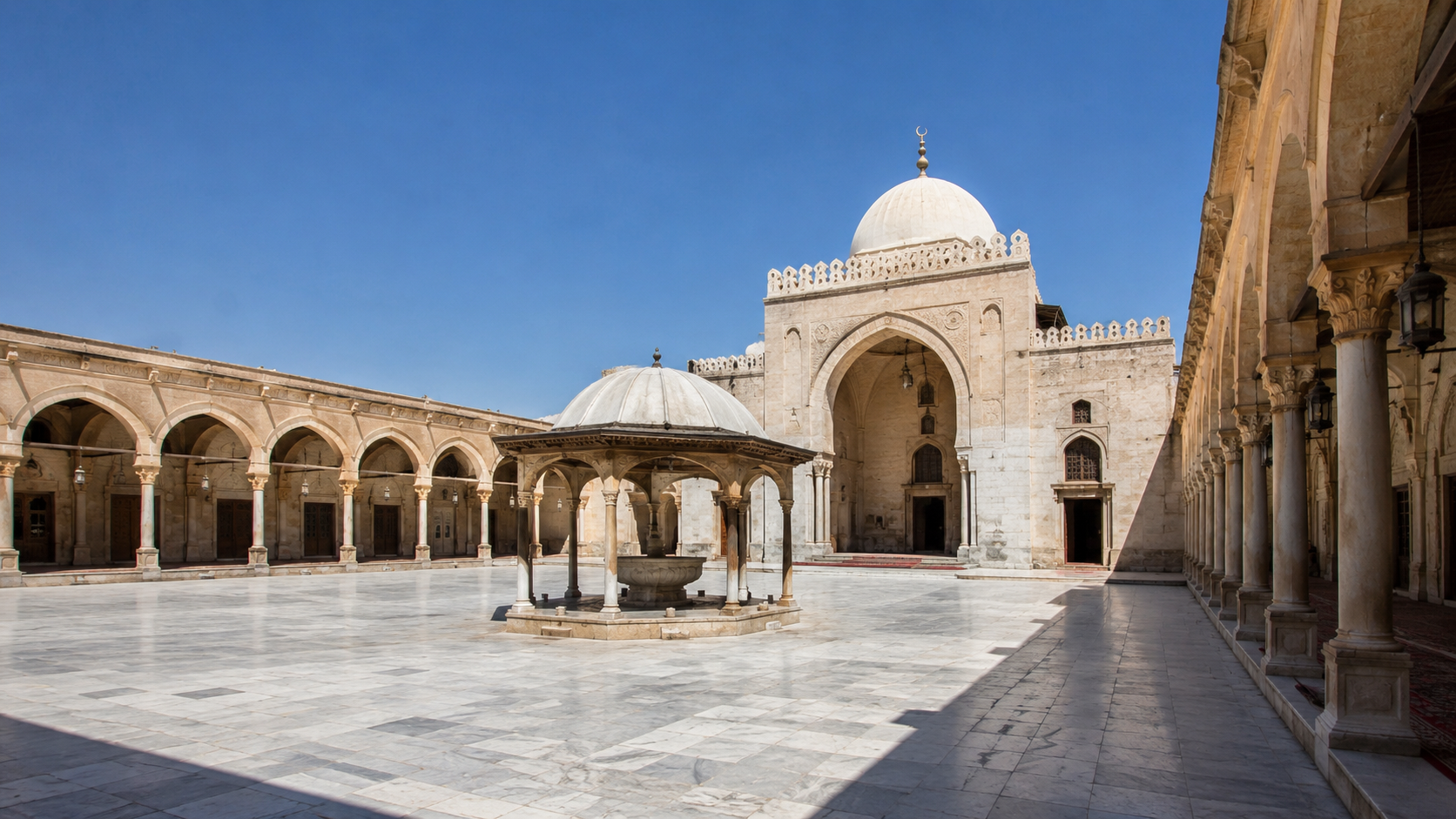 Open mosque courtyard with shaded arcades, central fountain, stone paving, and prayer hall approach showing how a sahn organizes light and shade.