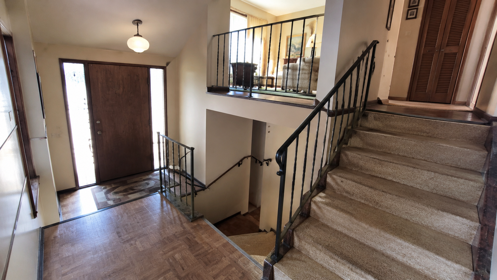 1970s split-level entry with tight stairs, dated railing, carpeted steps, and limited natural light.