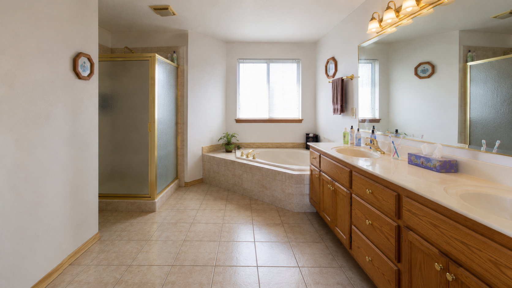 1990s primary bathroom with separate shower, deck tub, oak vanity, beige tile, and large mirror.
