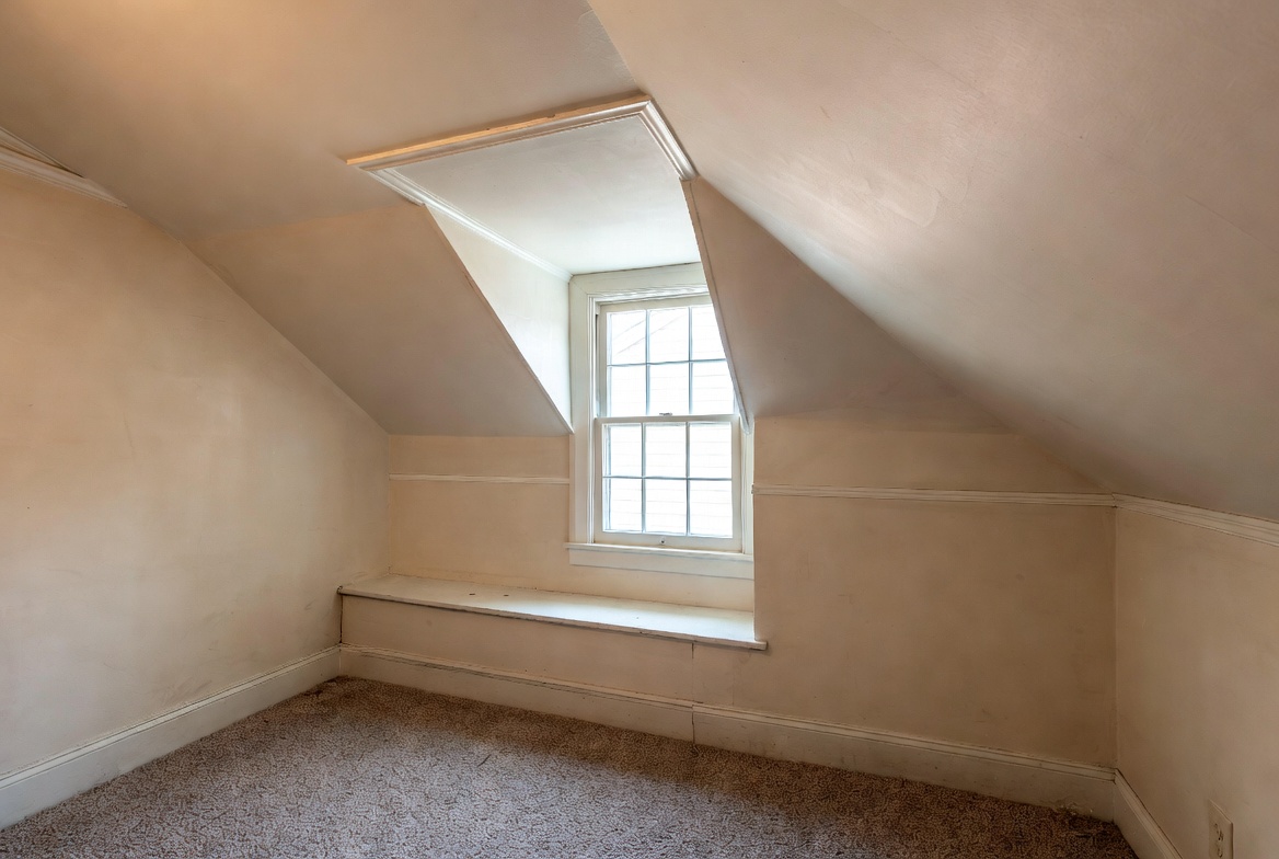 Upstairs Cape Cod room with sloped ceiling, knee wall, low headroom, and small window.