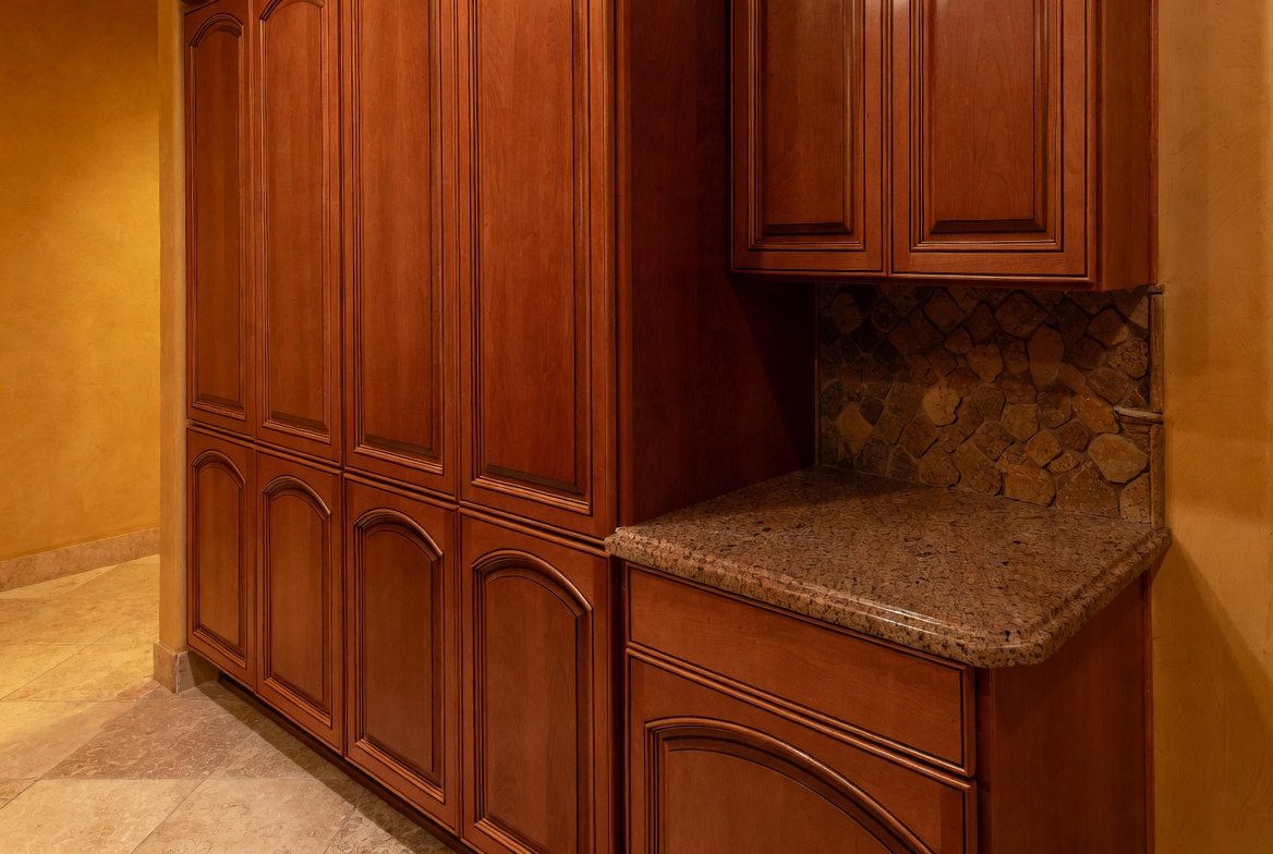 Cherry cabinet wall in a 2000s Tuscan kitchen with granite counter and stone backsplash.