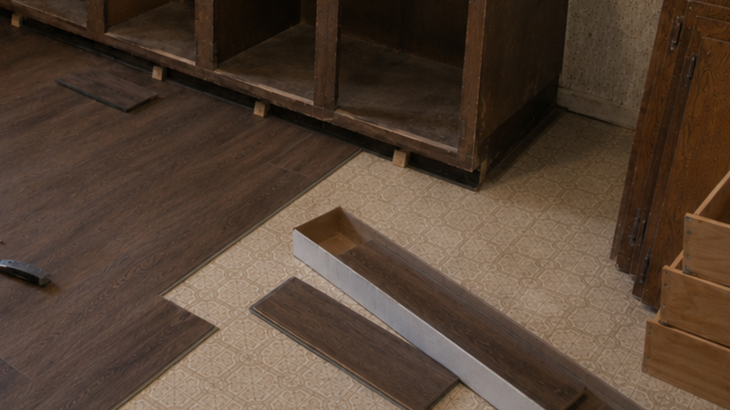 Dark vinyl plank flooring being installed over an old 1970s kitchen floor during a budget update.