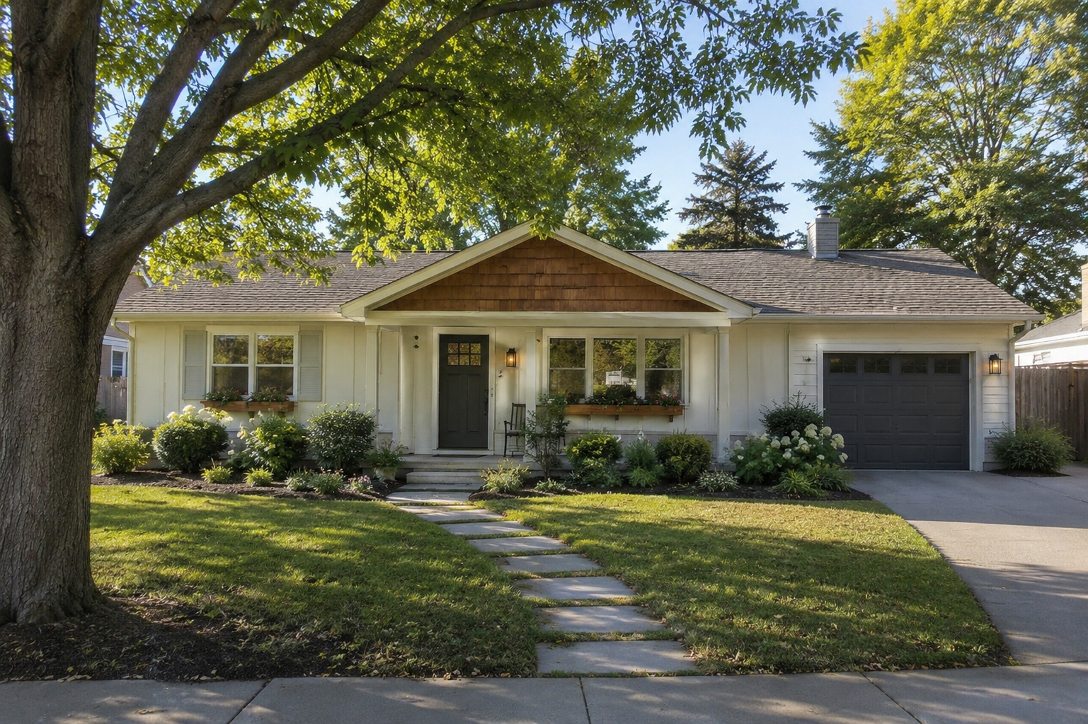 Updated 1980s ranch exterior with front garage, cedar gable, dark garage door, and shaded front yard.