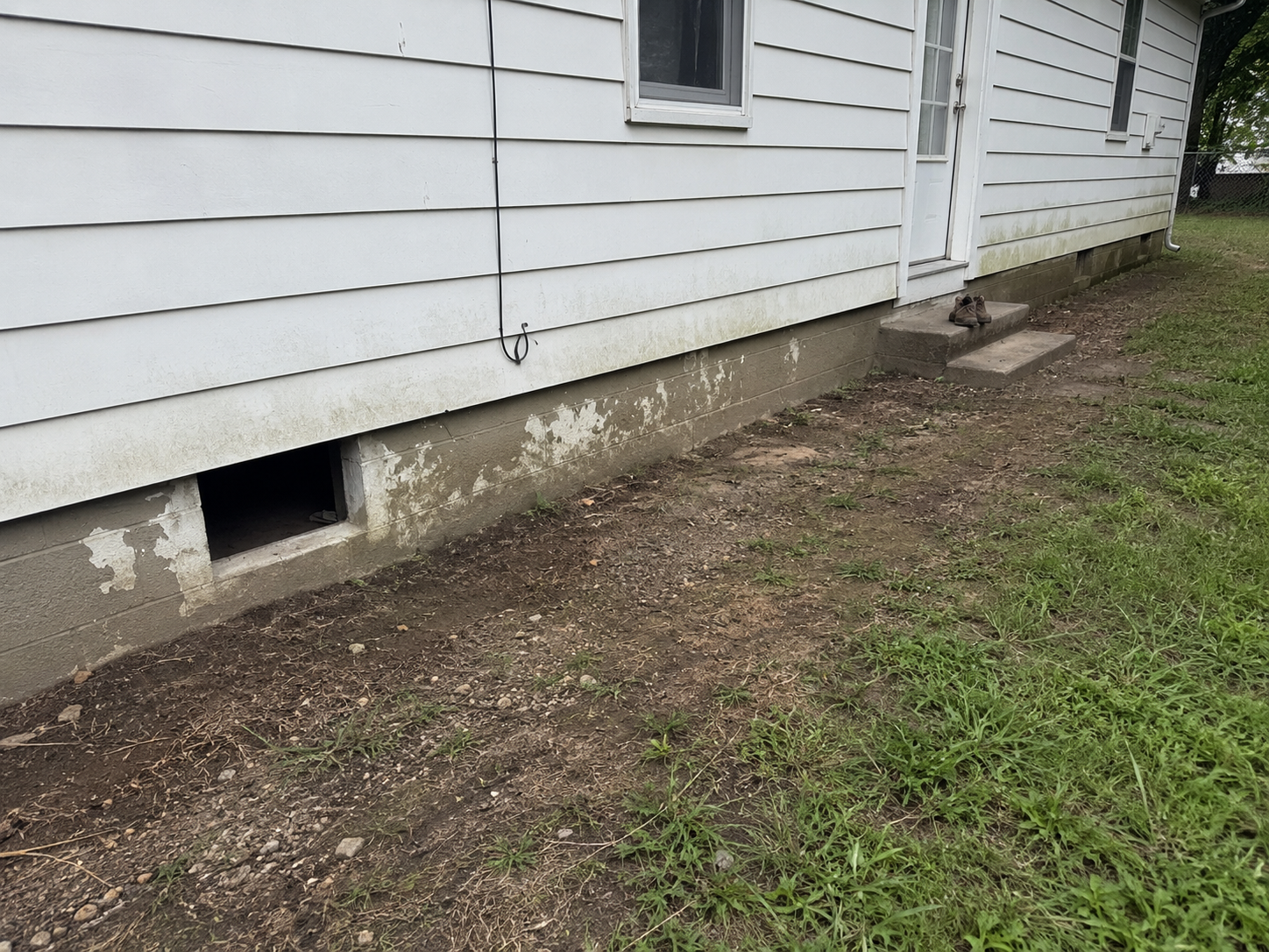 Older house with low foundation, damp grade, and limited crawl-space access.