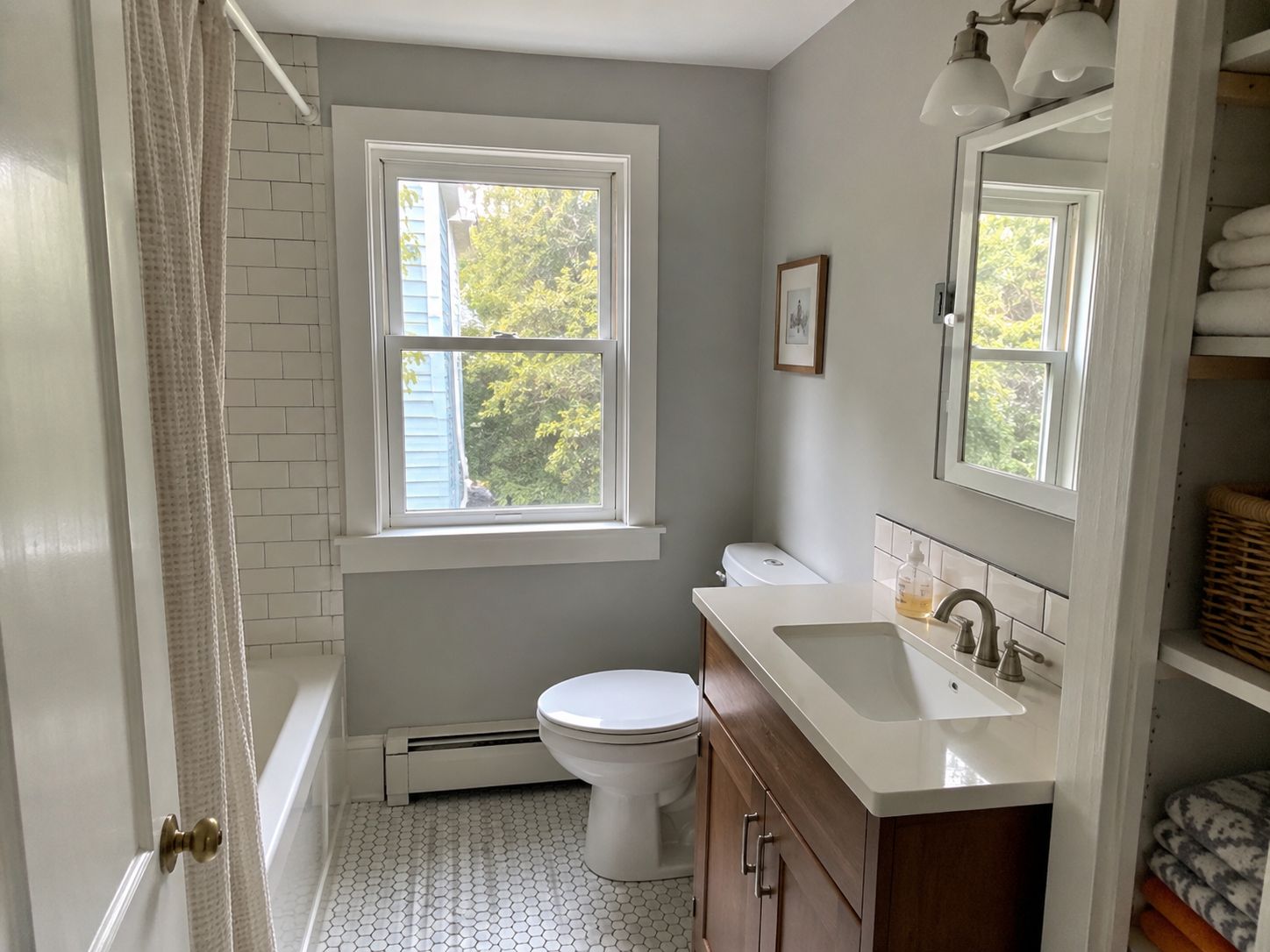 Small Cape Cod bathroom after remodel with compact vanity, tub, and natural daylight.