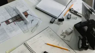 Modern architect’s office table with blueprints, laptop, and drafting tools
