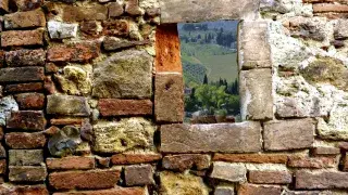 Stone structure forming a window-like opening that frames surrounding greenery.