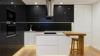 Modern kitchen with black cabinets, white countertops, wood accents, and minimalist lighting