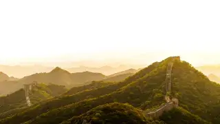 Great Wall of China viewed from a unique angle with sunlight and greenery.