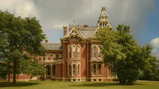Restored real Victorian mansion exterior with red brick walls, slate roof, and decorative trim.