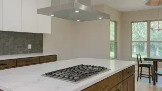 Kitchen with natural stone benchtop, modern wood cabinets, and updated flooring in an open, bright layout.