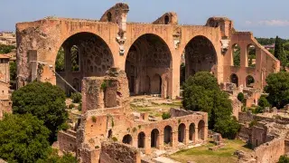 Aerial view of Basilica of Maxentius ruins showing colossal arches, coffered vaults, and surrounding structures.