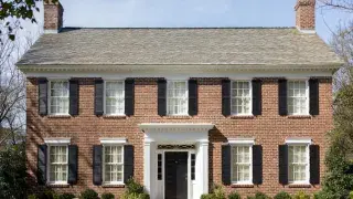 Colonial Revival house with symmetrical facade, side-gabled roof, centered entry, shutters, and dentil cornice.