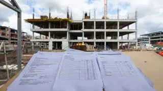 Bid documents and contractor pricing sheets on a site table during construction tender review and award planning.