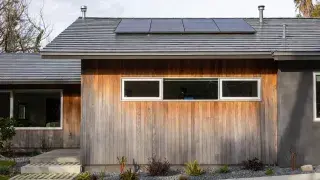 Renovated older house facade with upgraded windows, durable cladding, and clean energy-conscious detailing.
