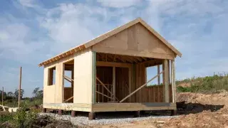 Small workshop frame raised on piers above gravel instead of a full concrete pad.