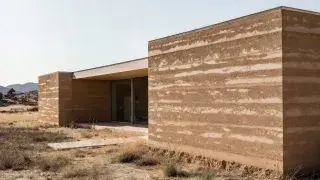 Modern rammed earth house with thick monolithic walls designed for sustainable living.