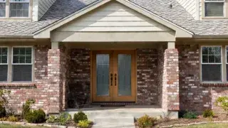 Reclaimed thin brick veneer on modest suburban home front entry with modern double doors.